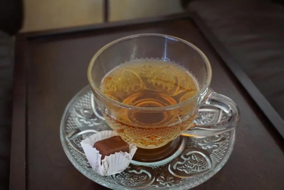 Cup of tea and a chocolate on a glass saucer, served on arrival